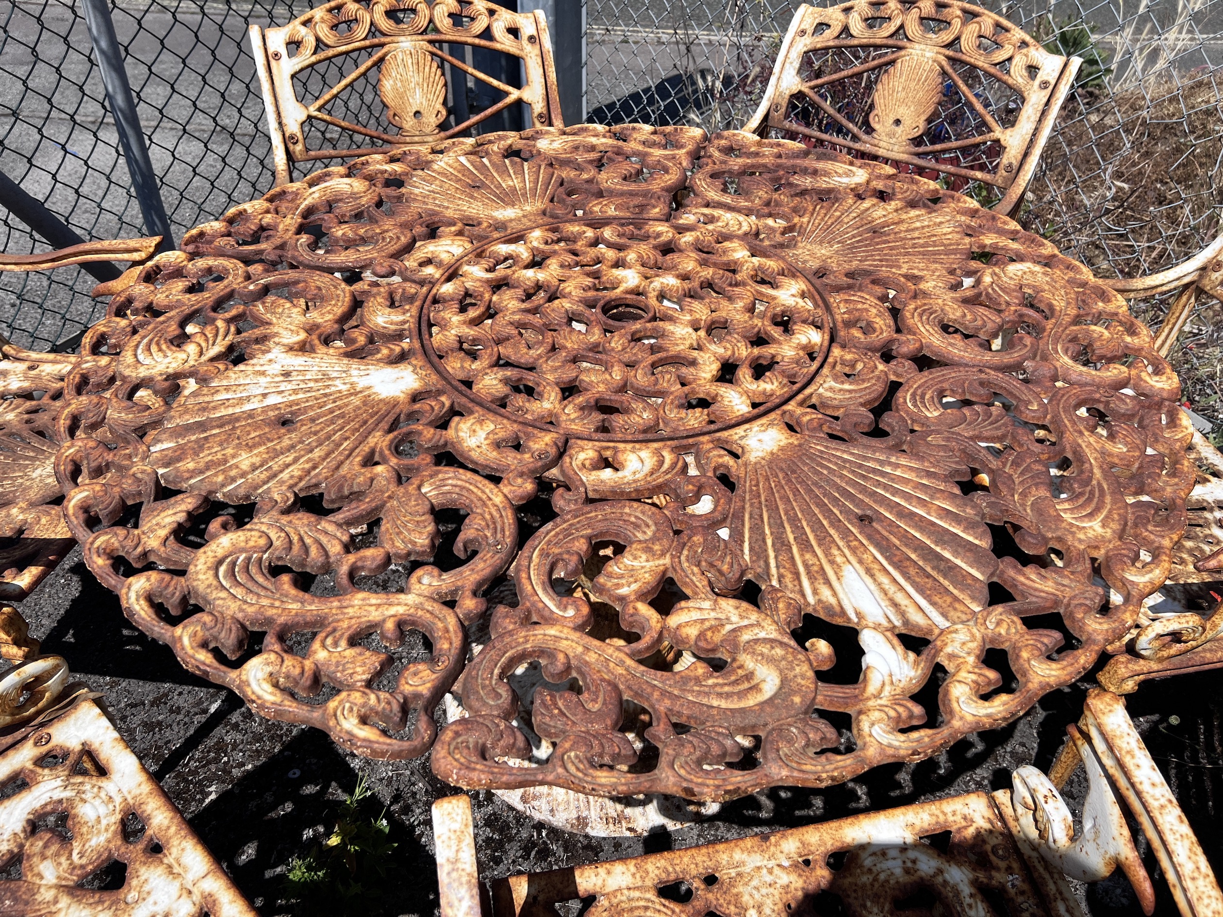 A Victorian style circular painted cast iron garden table, diameter 20cm, height 66cm and six chairs, cast with scallop shells and dolphins